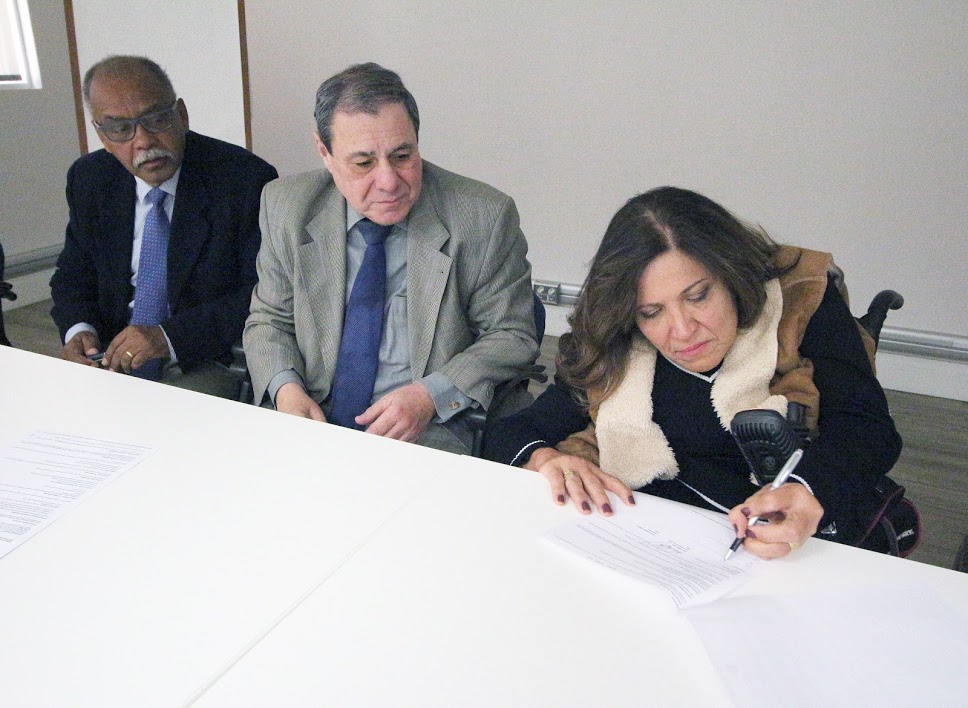 três pessoas na foto, a presidente da Comissão Permanente de Acessibilidade (CPA), Silvana Cambiaghi, assina o termo.